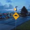 Solar-powered traffic beacon on side of road flashing amber to highlight sign