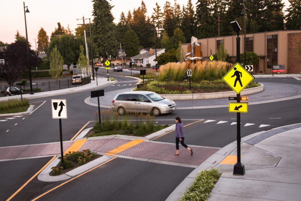 Woman crossing the street near a solar RRFB system.