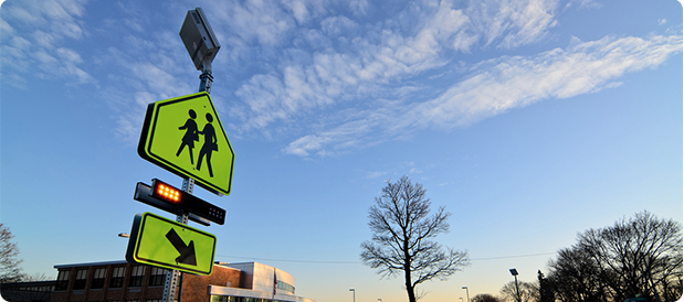 School zone sign with flashing beacon in daylight.