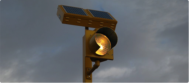 Amber round beacon with a solar engine on a pole at night.