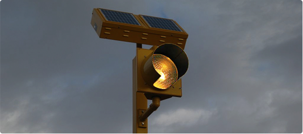 Amber round beacon with a solar engine on a pole at night.