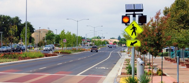 Crosswalk with flashing beacons powered by a solar panel.