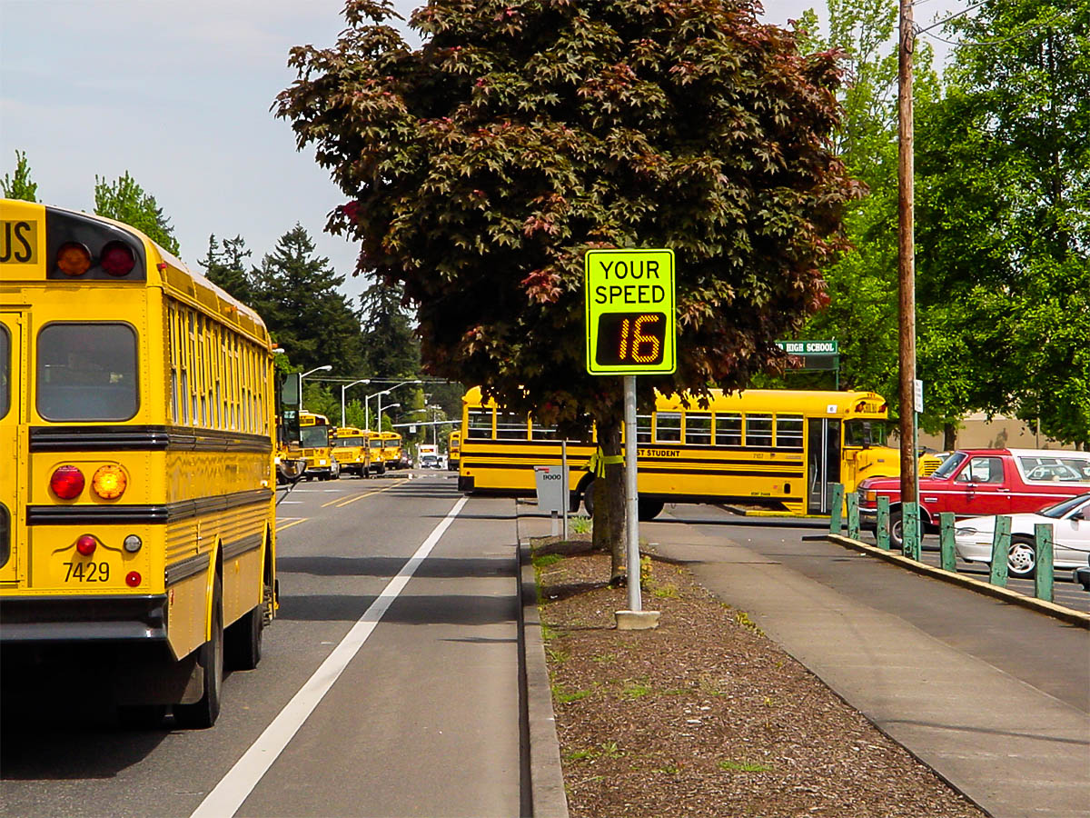 speedcheck radar sign and school buses pulling into school at a school in tigard, oregon