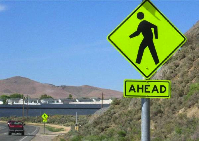 pedestrian crossing warning sign shown against blue sky