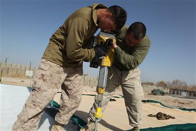 Marines drive a stake into the ground during work on a helicopter landing zone