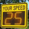 A digital "YOUR SPEED" radar speed sign with bright LEDs outdoors